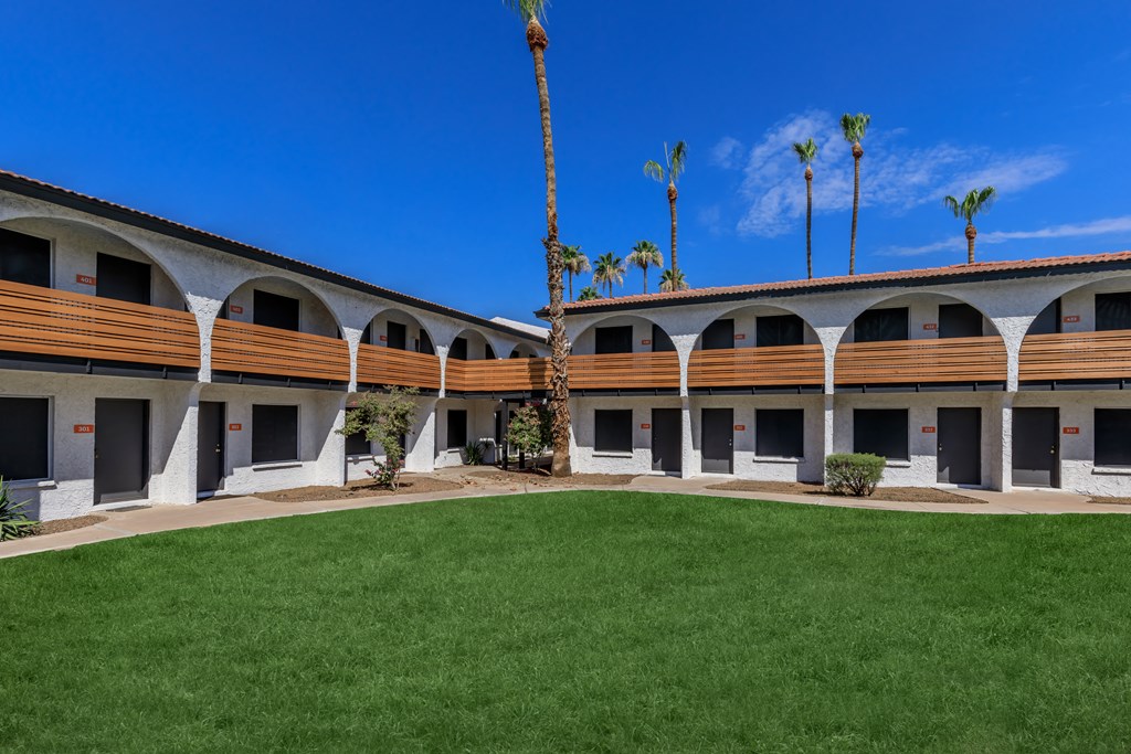 a courtyard with a grassy area and palm trees in the background
