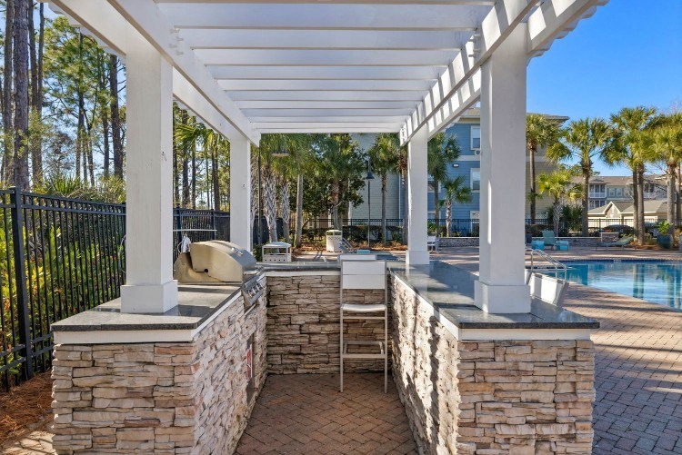 the pool is under a covered patio with stone walls