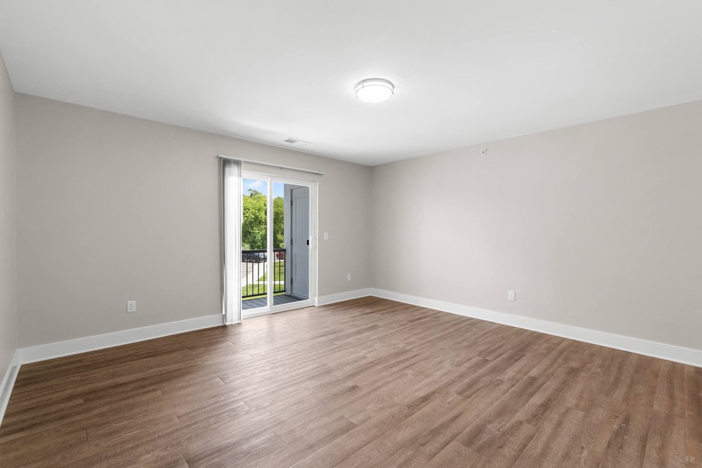 a living room with wood floors and a door to a balcony