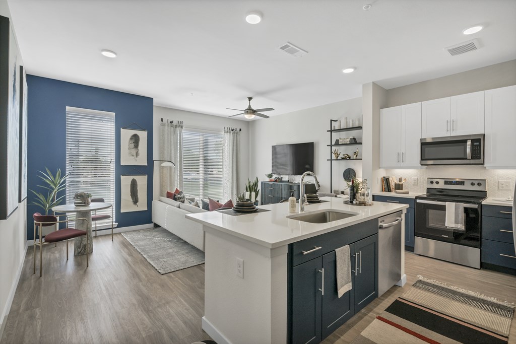 A modern kitchen with dark blue walls and white countertops.