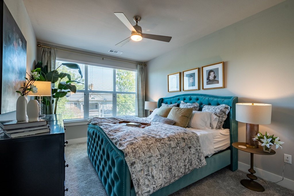 A bedroom with a bed, nightstand, and a ceiling fan.