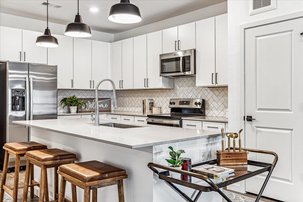 a kitchen with white cabinets and a counter with bar stools