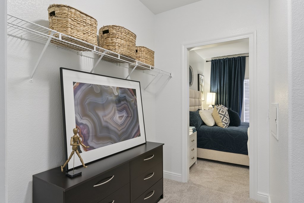 A framed artwork with a purple and white design is on a black dresser.