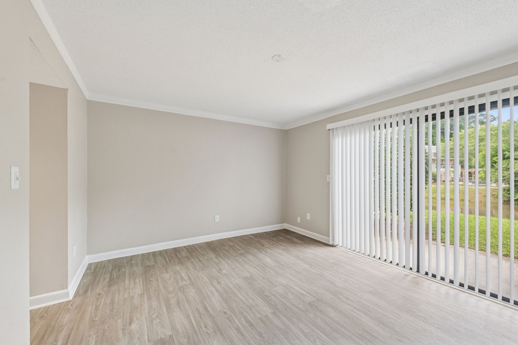 A room with a sliding glass door and wooden flooring.