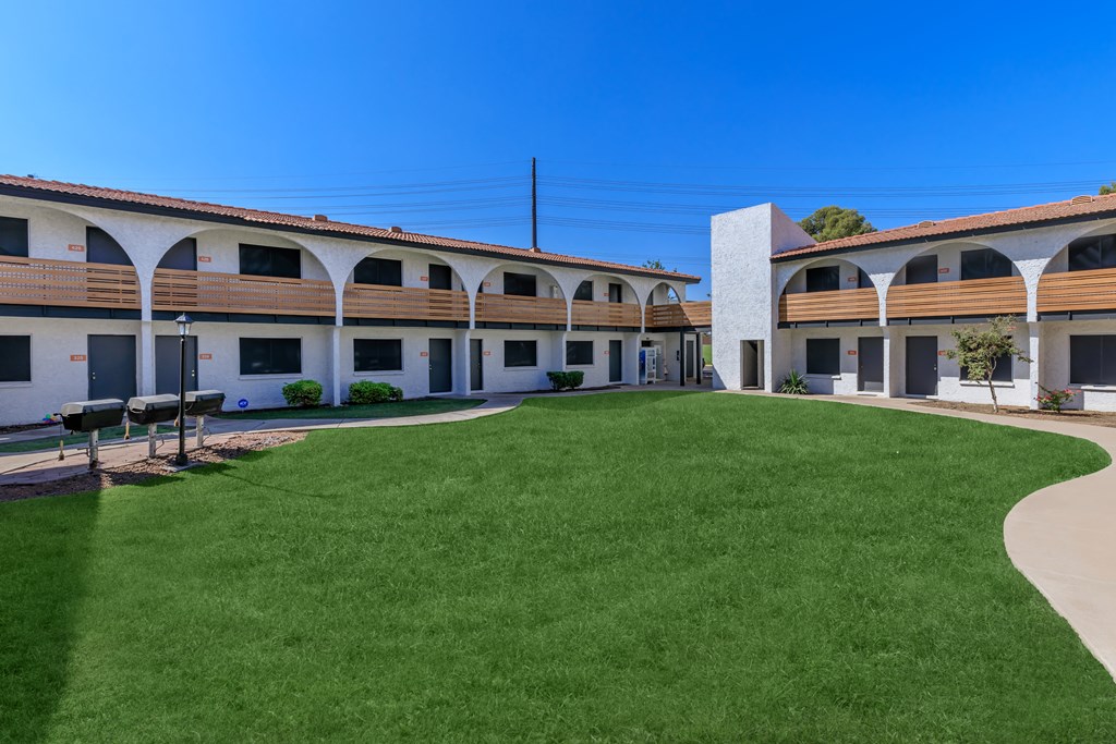 a courtyard with a grassy area and a building in the background