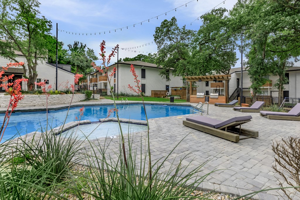 a swimming pool with lounge chairs and trees in the background