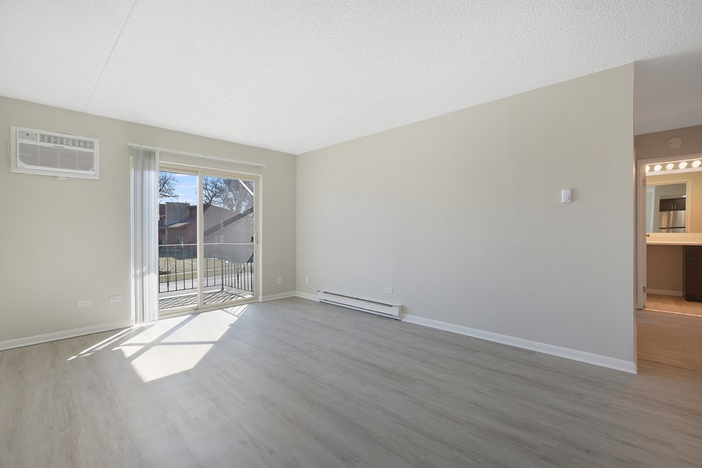 an empty living room with a sliding glass door to a balcony