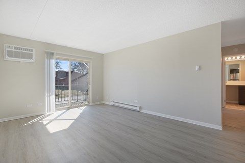 an empty living room with a sliding glass door to a balcony