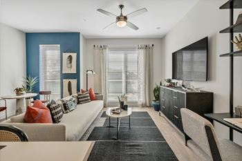 A living room with a beige couch, a coffee table, and a ceiling fan.