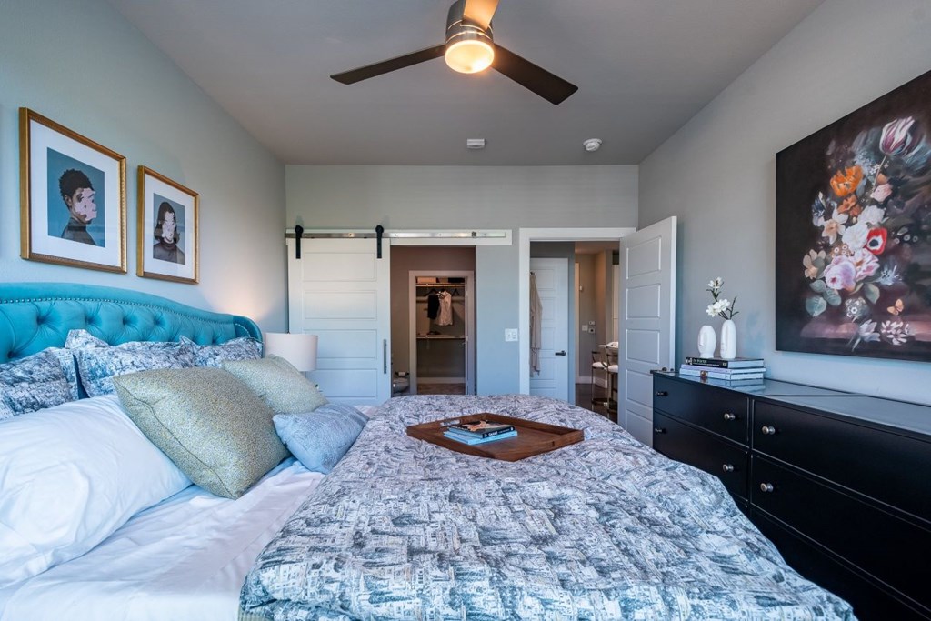 A bedroom with a bed, dresser, and ceiling fan.