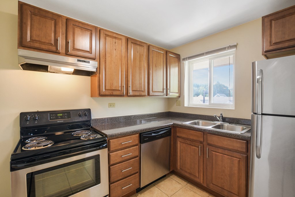 a kitchen with wooden cabinets and stainless steel appliances and a window