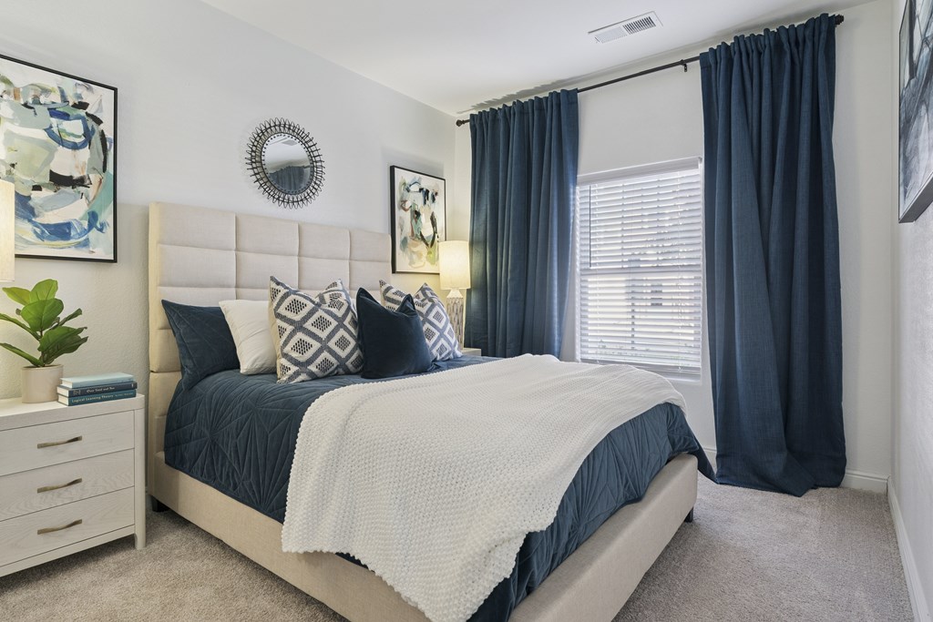 A bedroom with a large bed and a white headboard.