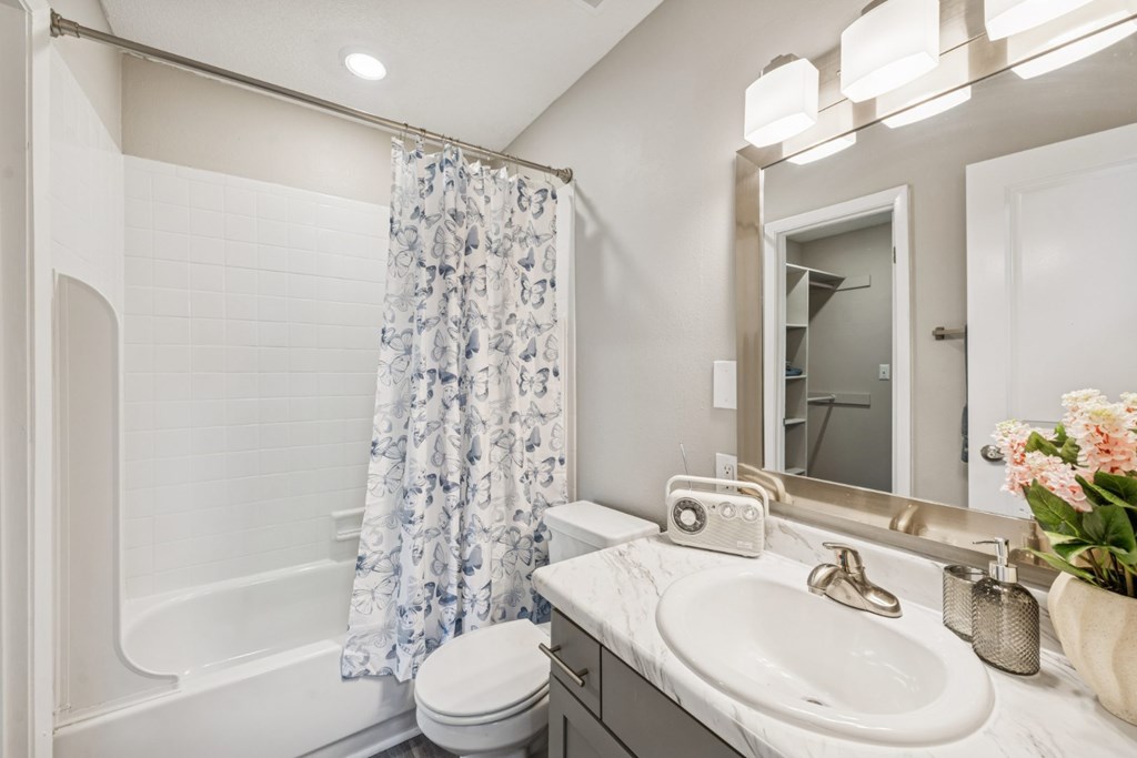 A white bathroom with a toilet, sink, and shower.