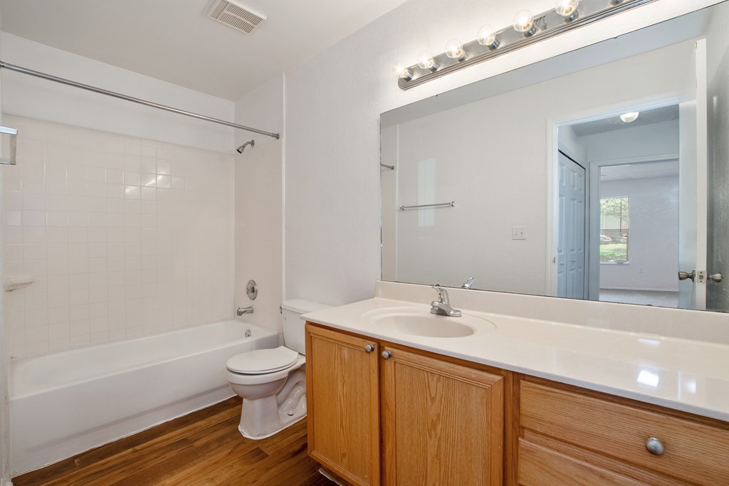 A white bathroom with wooden cabinets and a white toilet.