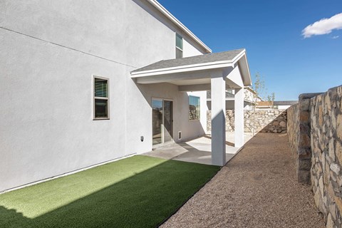A modern house with a white exterior and a stone wall.
