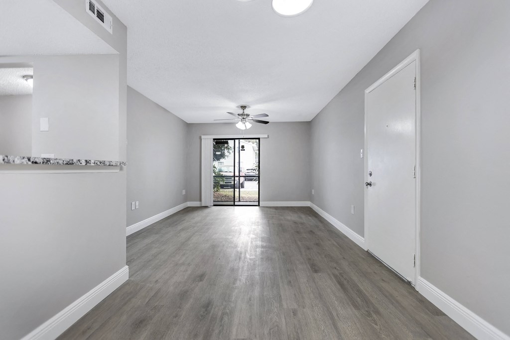 an empty living room with white walls and a ceiling fan