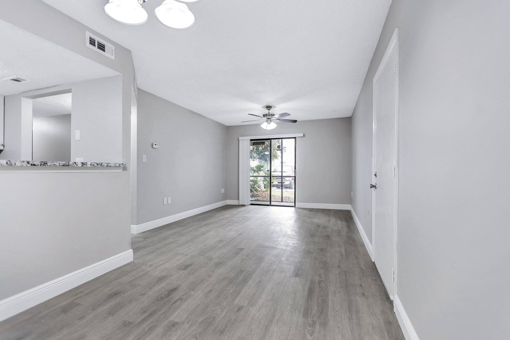 an empty living room with white walls and a ceiling fan
