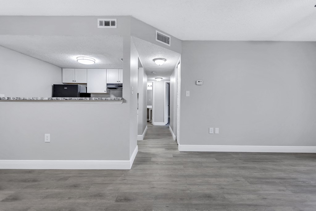 the living room and kitchen of an empty apartment