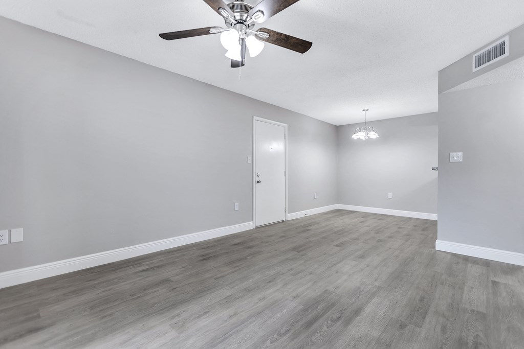the living room of an empty house with a ceiling fan