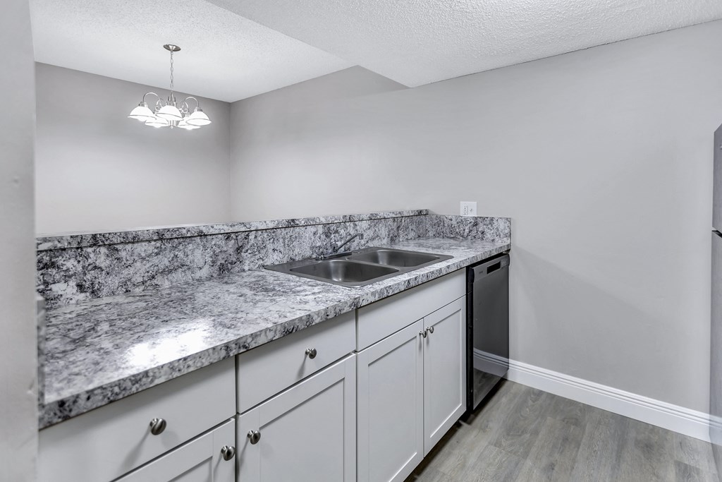 a kitchen with white cabinets and granite counter tops and a stainless steel sink