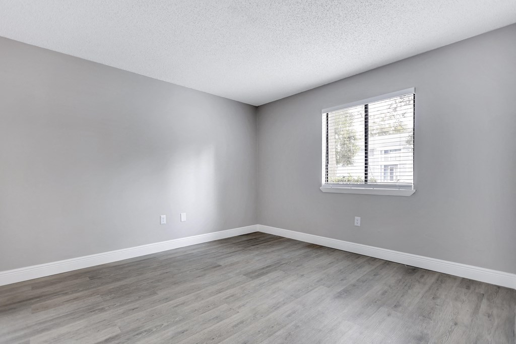 an empty room with wood floors and a window