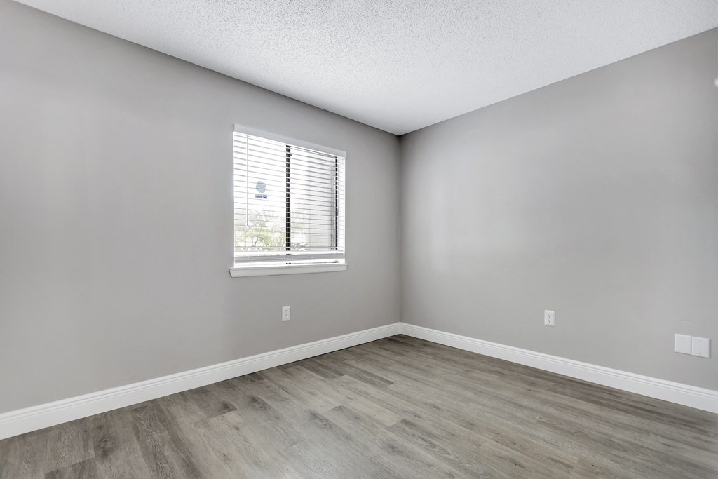 an empty room with wood floors and a window