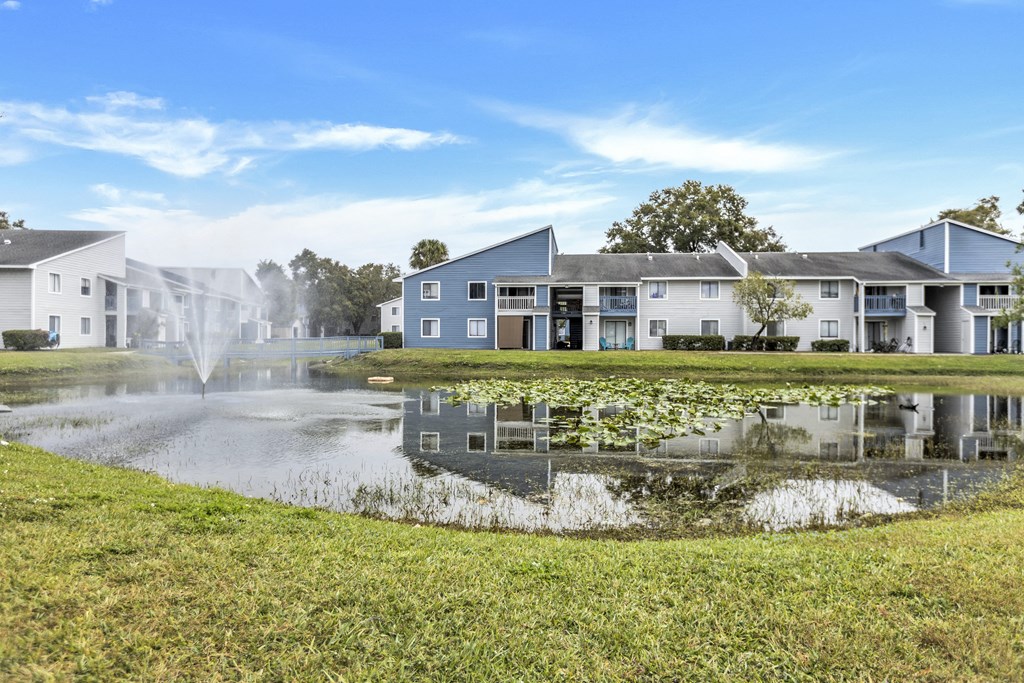 a pond with a fountain in front of apartment buildings