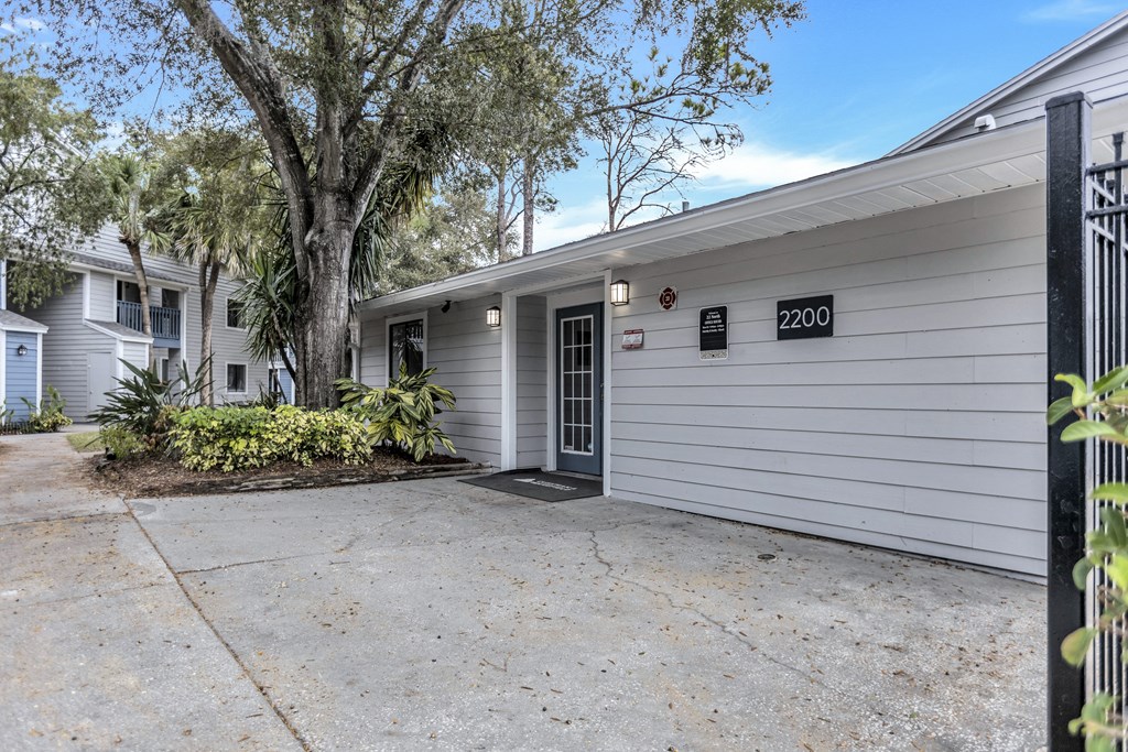 a white house with a driveway and a tree in front of it