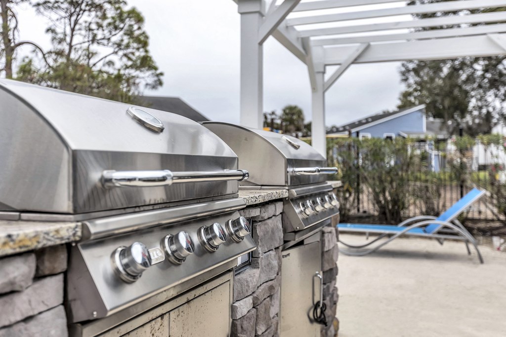two gas bbq grills in a backyard with a picnic table