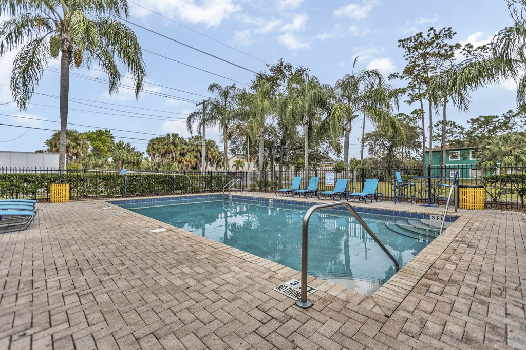 a swimming pool with blue chairs and palm trees