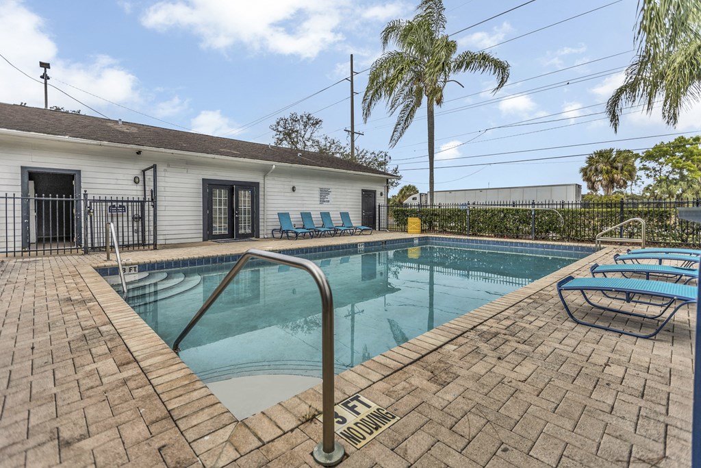 a swimming pool with chairs and a house in the background