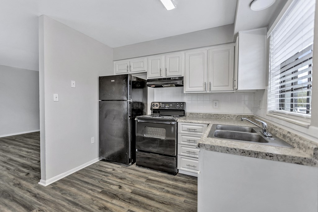 an empty kitchen with white cabinets and a black refrigerator