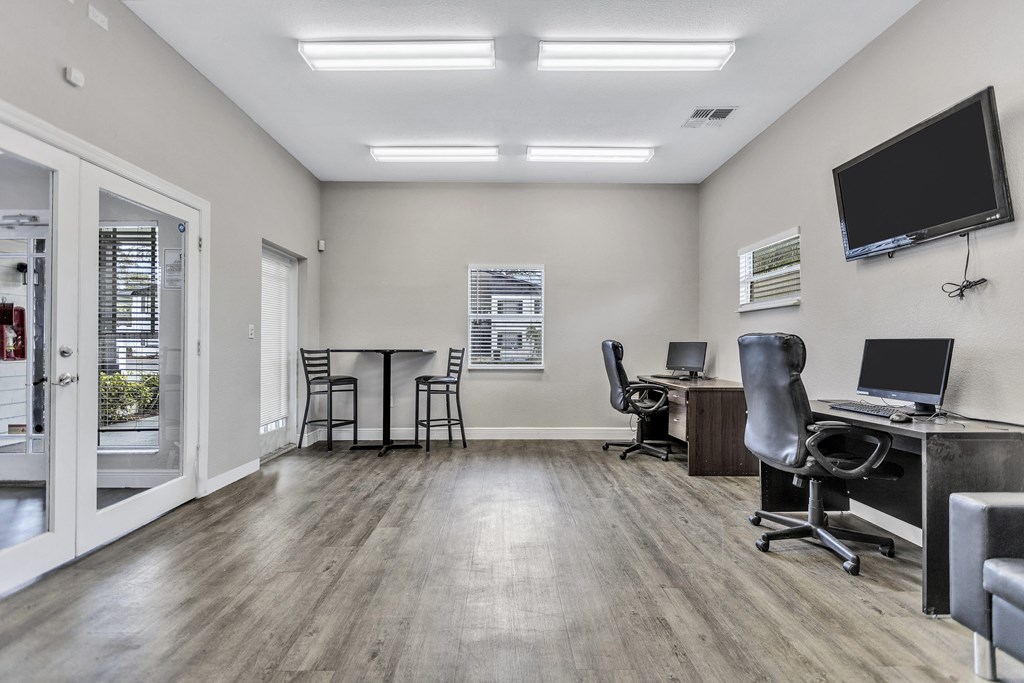 an office with two computers and a tv on the wall