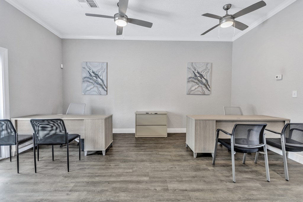 an office space with desks and chairs and a ceiling fan