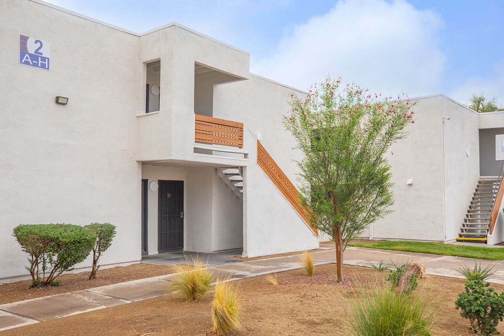 a building with a staircase and a tree in front of it