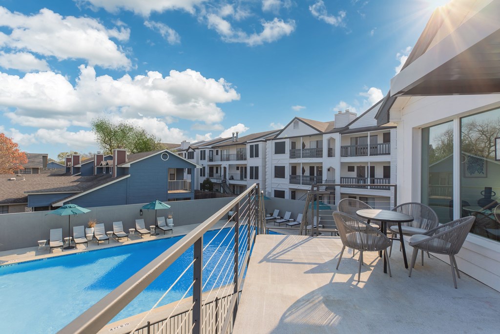a balcony with a pool and tables and chairs