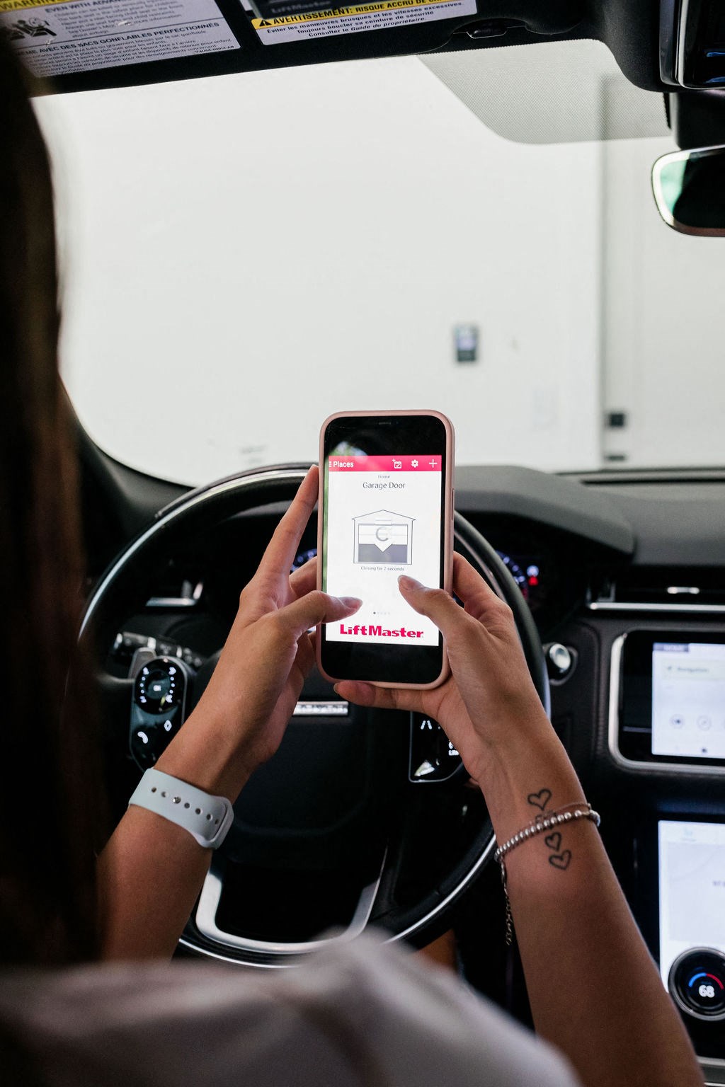 a woman in the drivers seat of a car holding a phone with the uber app on it