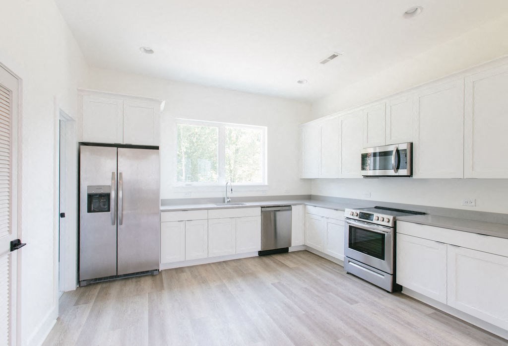 a kitchen with white cabinets and stainless steel appliances