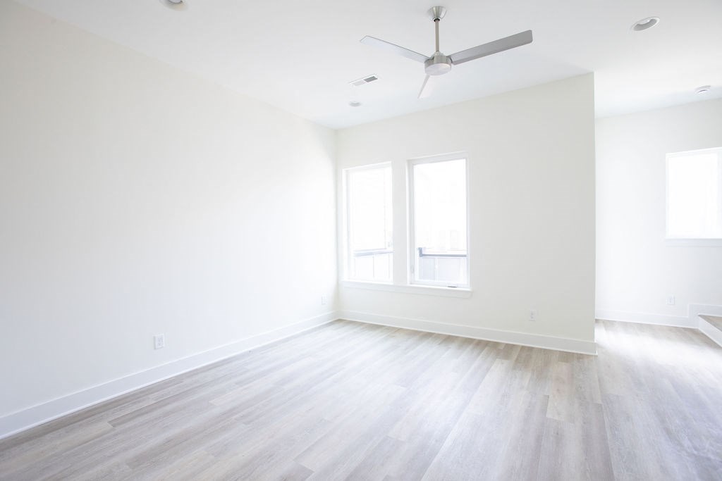 an empty room with white walls and a white ceiling fan