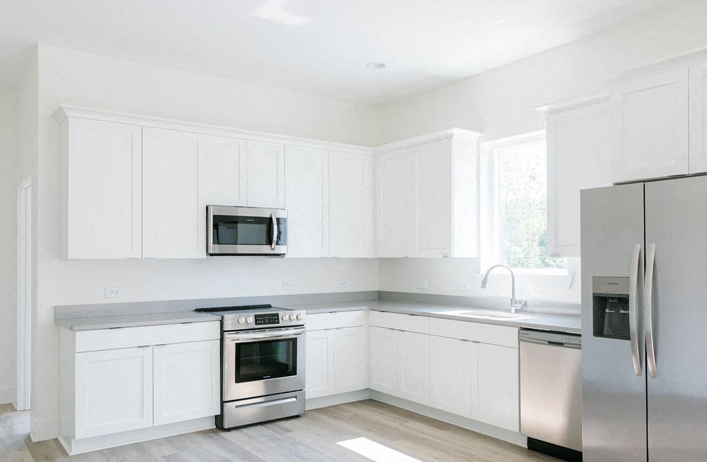 a kitchen with white cabinets and stainless steel appliances