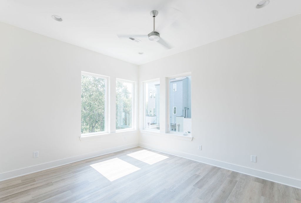 an empty room with three windows and a ceiling fan