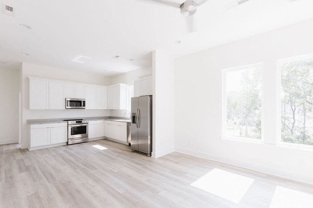 a kitchen with white cabinets and a stainless steel refrigerator