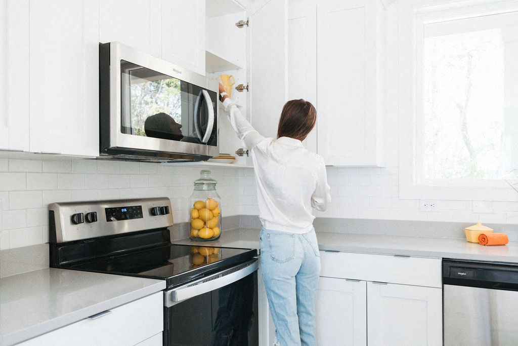 a woman cleaning a microwave in a kitchen