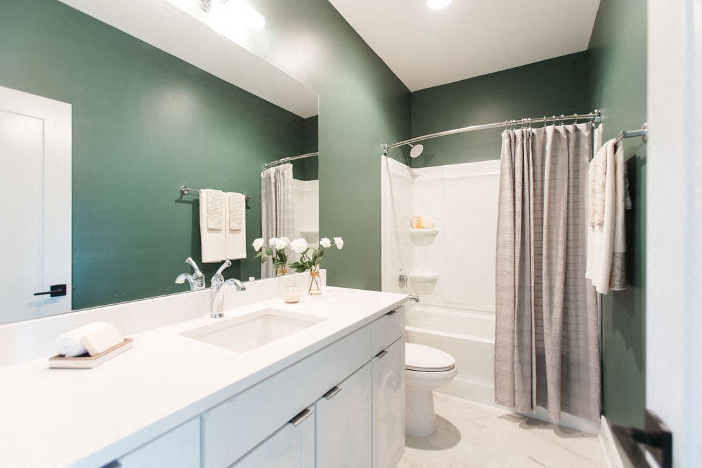 a bathroom with green walls and a white sink and toilet