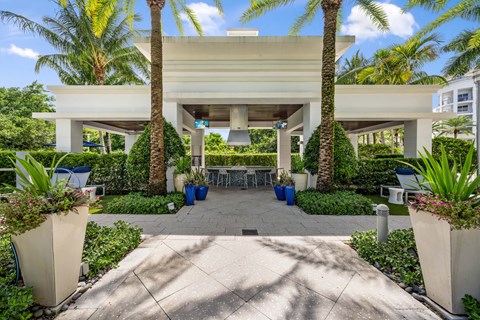 a patio with palm trees and a table and chairs under a building