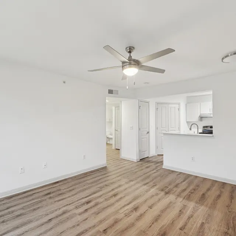 A room with a ceiling fan and wooden flooring.