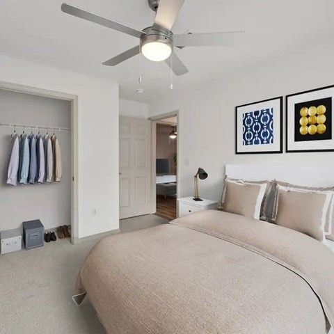 A bedroom with a beige bed and a ceiling fan.