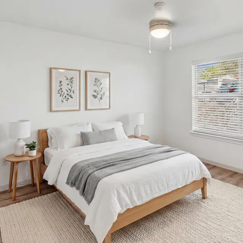 A bedroom with a large bed and two framed pictures on the wall.