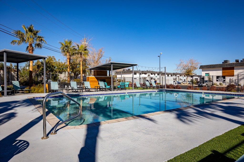 a swimming pool with lounge chairs and palm trees in the background