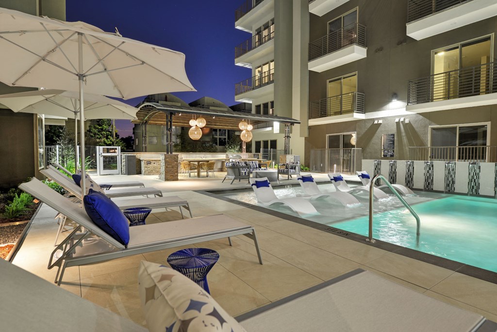 Pool with lounge deck and chairs at night